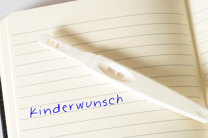 Ein Schwangerschaftstest und ein Notizbuch mit dem Wort Kinderwunsch